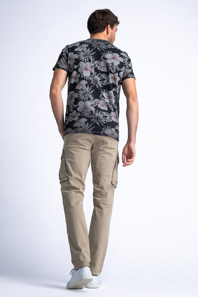 Pantalon cargo beige de Petrol Industries, avec poches latérales et porté avec un t-shirt à fleurs et des baskets blanches.
