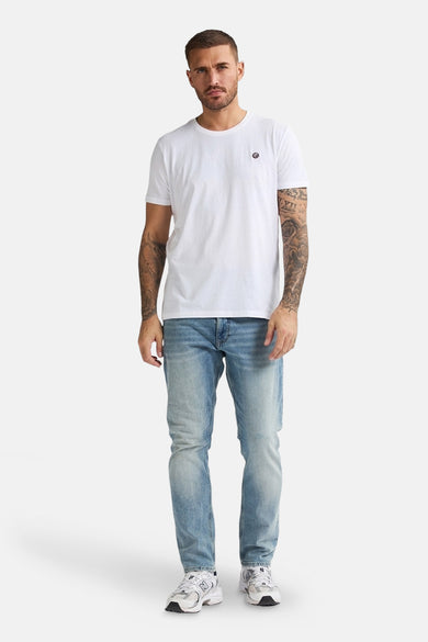 Slim-fit jeans in light blue denim from Petrol Industries, worn with a white t-shirt and white sneakers.