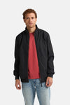 Zwarte Petrol Industries® jas met ritssluiting over een rood T-shirt en een lichtblauwe jeans.