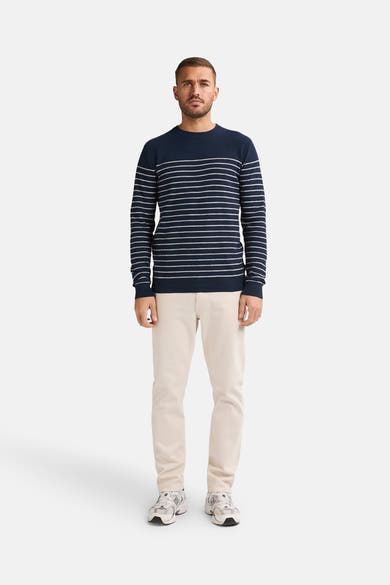 Ronde hals trui blauw van Petrol Industries met witte horizontale strepen, gedragen met een beige broek en sneakers.