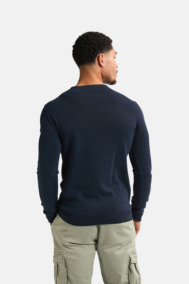 Pull à col rond bleu par Petrol Industries, détail du dos, porté avec un pantalon cargo vert kaki.