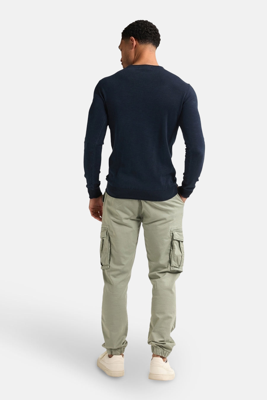 Pull à col rond bleu de Petrol Industries®, porté avec un pantalon cargo vert olive et des chaussures couleur crème.