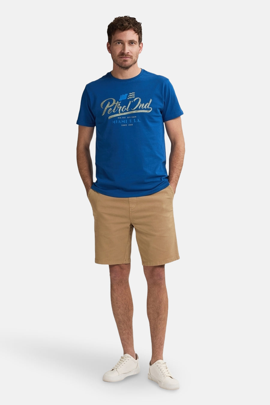 Korte beige short van Petrol Industries®, gedragen met een blauw T-shirt en witte sportschoenen.
