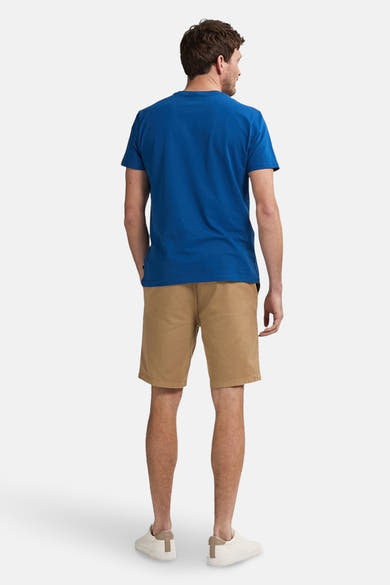 Korte beige short van Petrol Industries®, gedragen met een blauw T-shirt en witte schoenen, van achteren gezien.