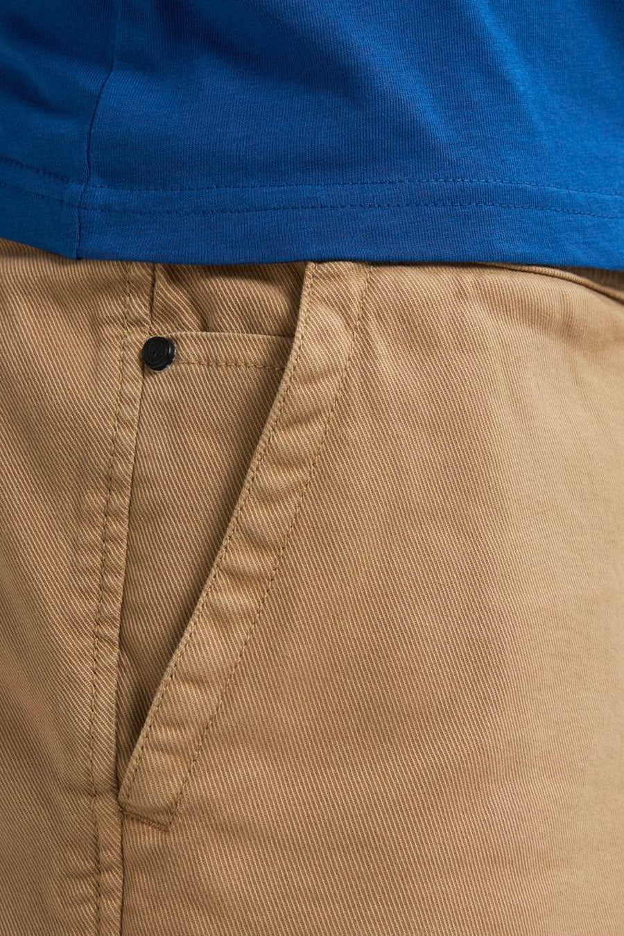 Korte beige short van Petrol Industries® in canvas, met een zak met knoopsluiting en een zichtbaar blauw T-shirt aan de bovenkant.