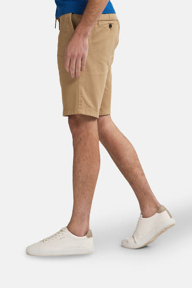 Korte beige short van Petrol Industries®, gedragen met witte sportschoenen.