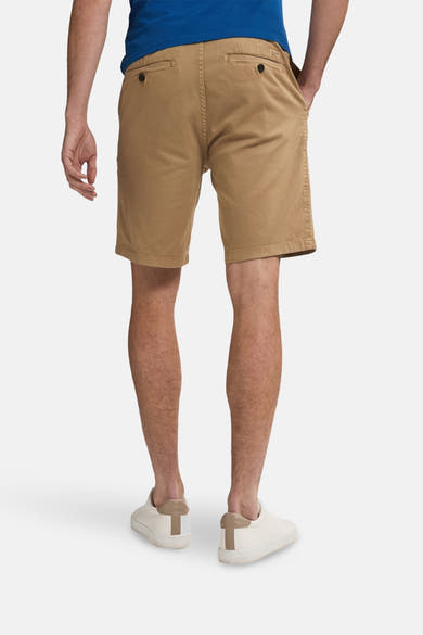 Korte beige short van Petrol Industries, met achterzakken met knopen en witte schoenen.