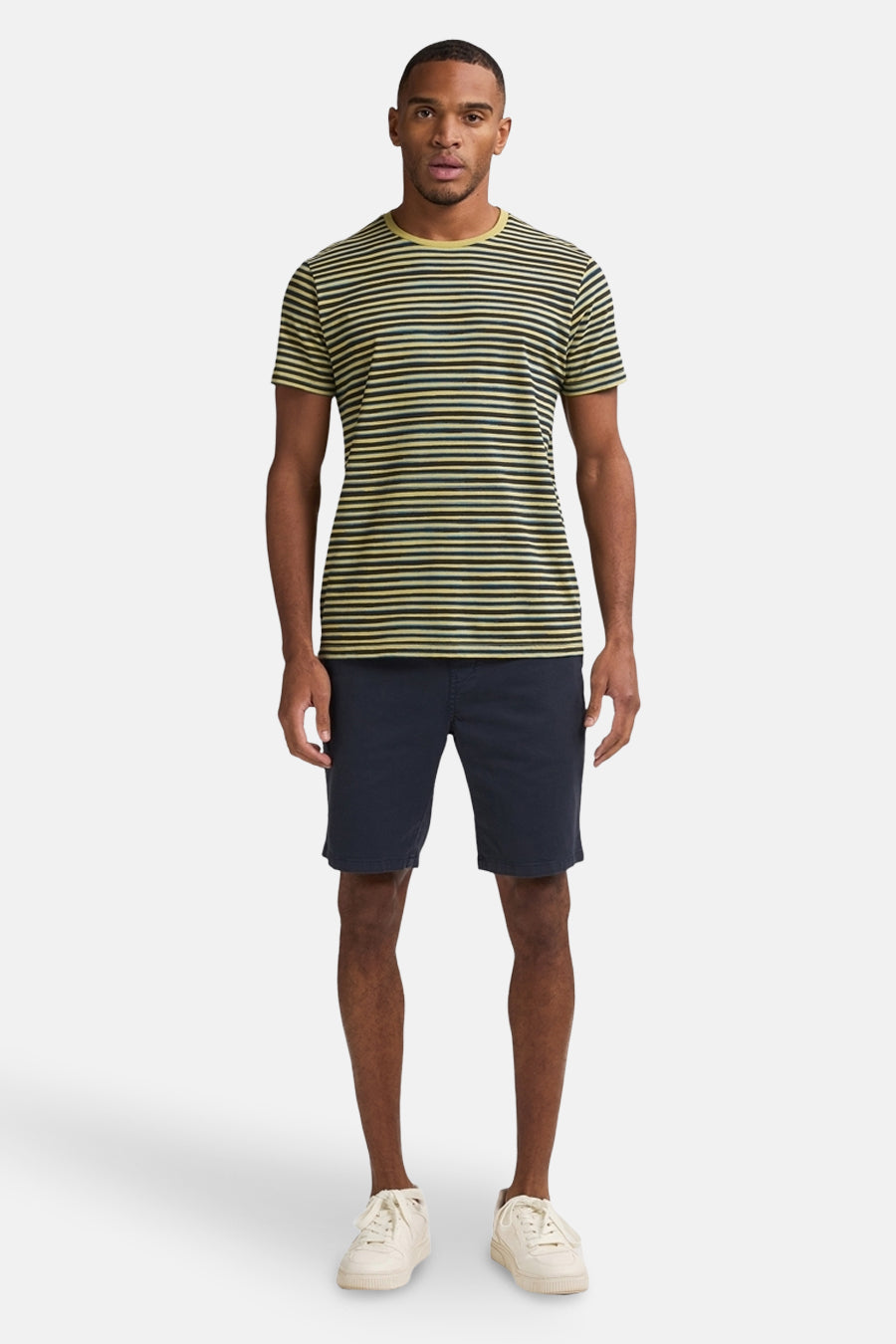 Korte blauwe spijkerbroek van Petrol Industries, gedragen met een gestreept T-shirt en witte schoenen.