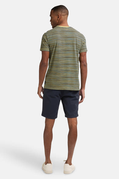 Korte blauwe spijkerbroek van Petrol Industries, gedragen met een gestreept T-shirt en beige espadrilles, van achteren gezien.