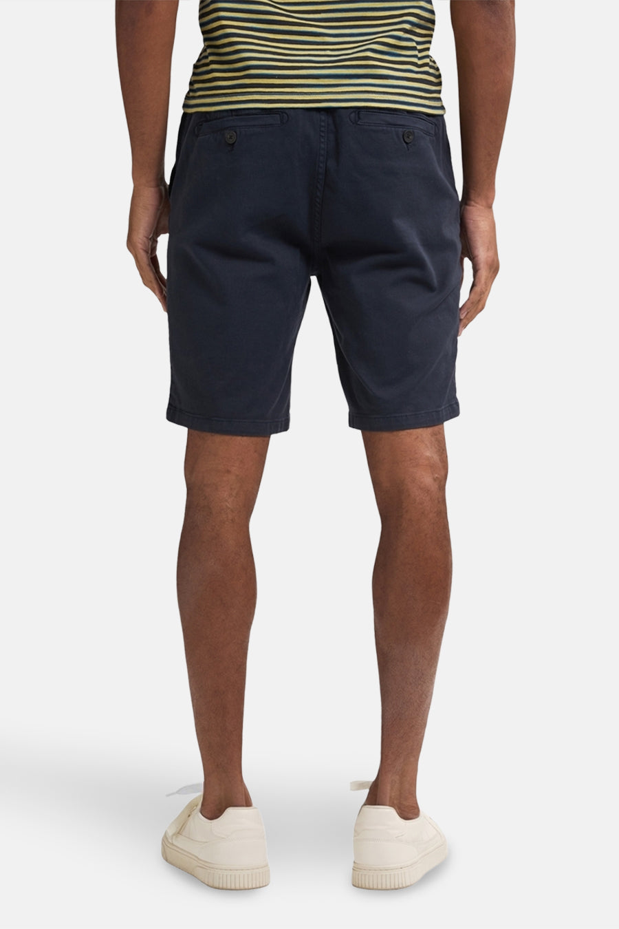 Korte blauwe jas van Petrol Industries gedragen met een gestreept T-shirt en witte sneakers, achtergezien.