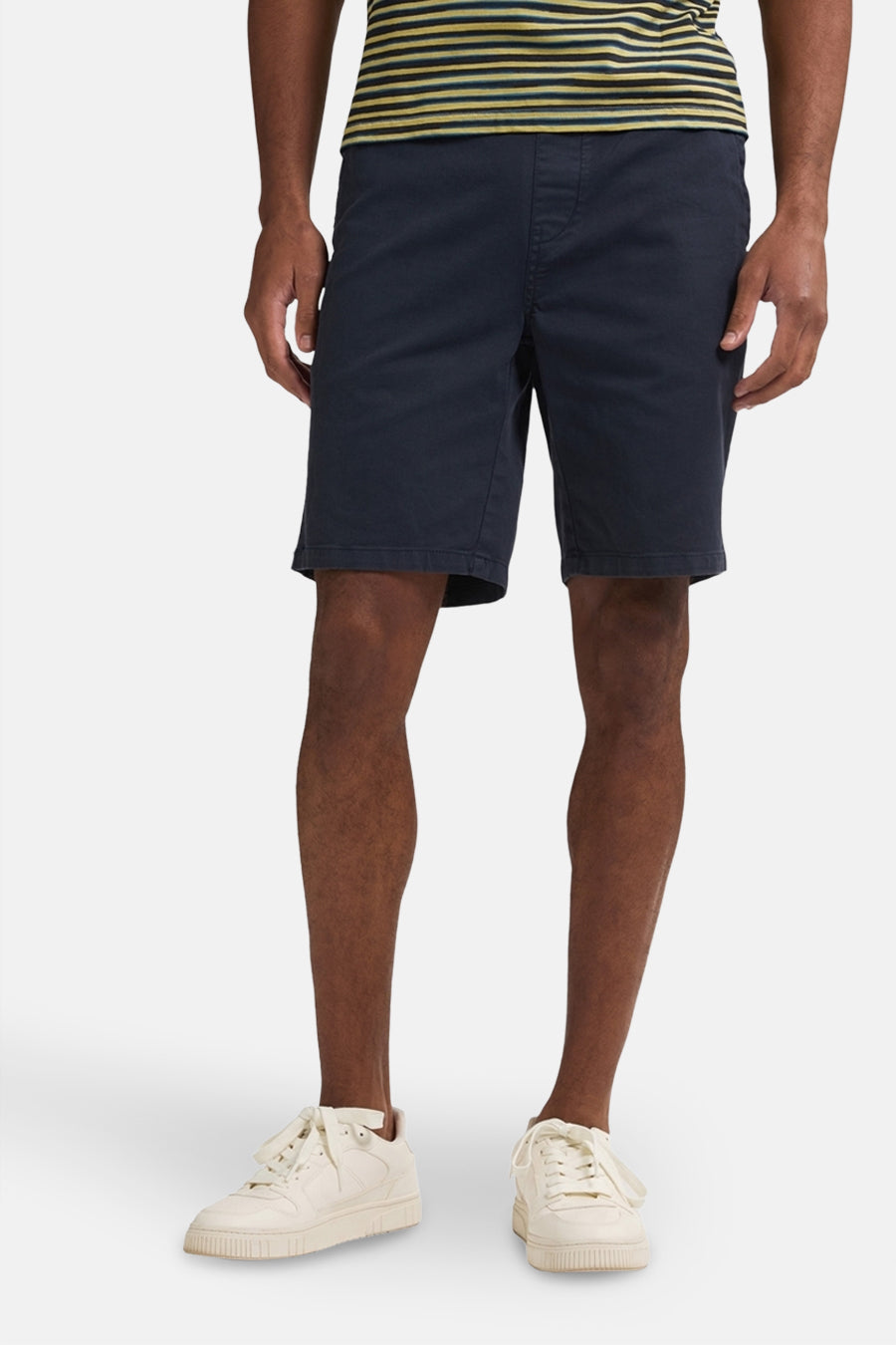 Korte blauwe broek van Petrol Industries, gedragen met een gestreept T-shirt en witte sportschoenen.
