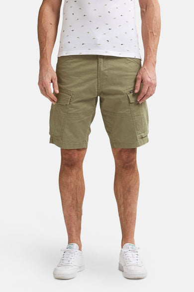 Korte kaki van Petrol Industries, met een bruine gevlochten riem en een geborduurd vismotief op het witte poloshirt.