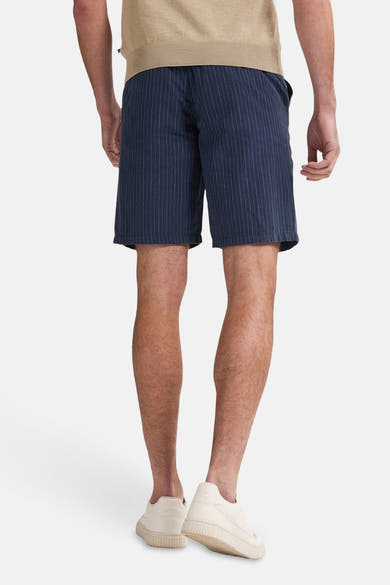 Short bleu à rayures verticales par Petrol Industries, porté avec un haut beige et des baskets crème, vue de dos.
