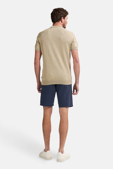 Korte blauwe broek met verticale strepen van Petrol Industries, gedragen met een beige T-shirt en crèmekleurige sneakers.