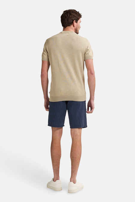 Korte blauwe broek met verticale strepen van Petrol Industries, gedragen met een beige T-shirt en crèmekleurige sneakers.