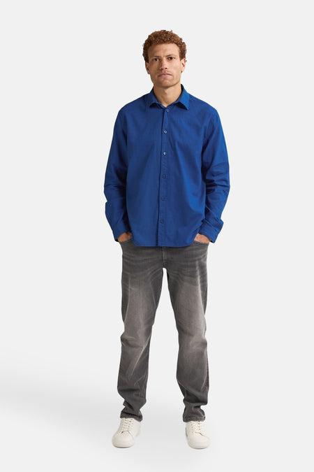 Blauw overhemd met lange mouwen van Petrol Industries, gedragen met een grijze broek en witte schoenen.