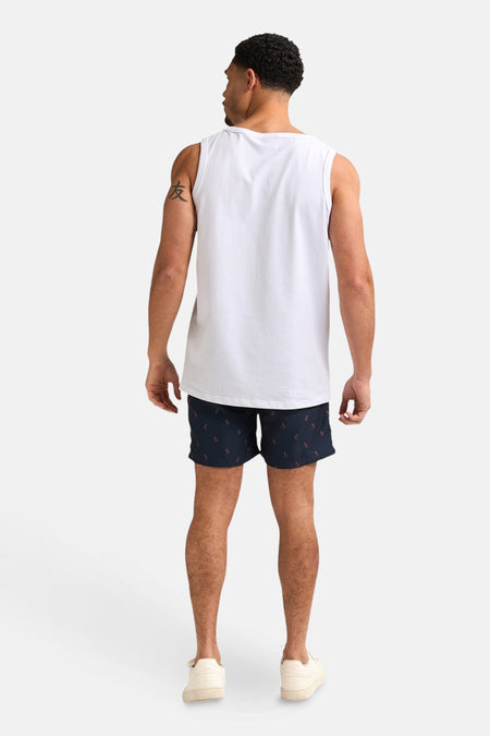 Donkerblauwe zwembroek van Petrol Industries, met discreet patroon, gedragen met een witte tanktop en sneakers.