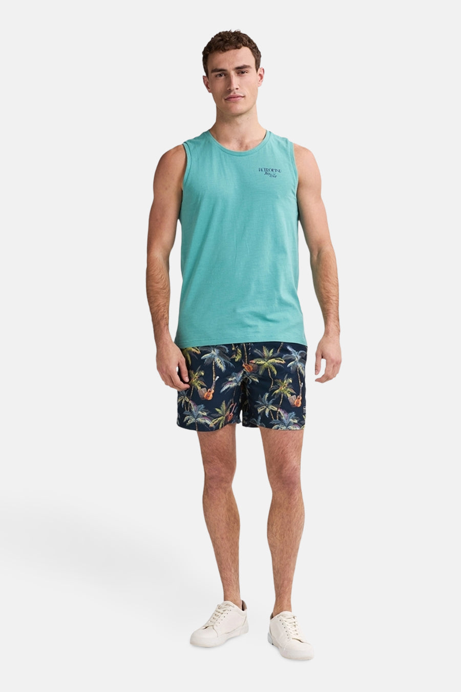Blauwe zwembroek met palmboomprint van Petrol Industries, gedragen met een turquoise tanktop en witte sneakers.