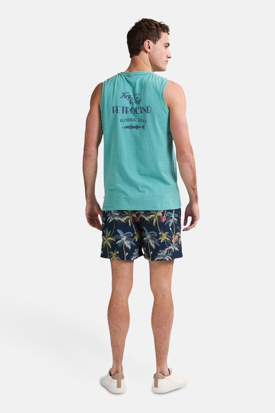 Blauwe zwembroek met palmboomprint van Petrol Industries®, gedragen met een turquoise tanktop en witte schoenen.