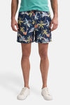 Marineblauwe zwembroek van Petrol Industries® met palmboom- en gitaarmotief, gedragen met een groen T-shirt en witte schoenen.