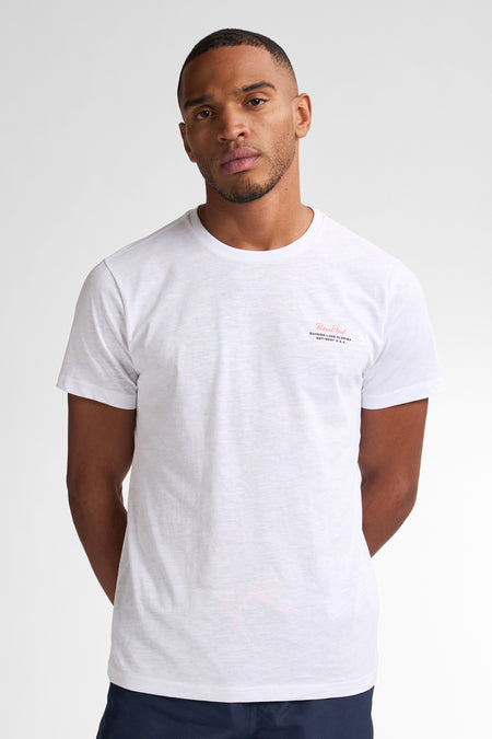 Wit T-shirt met korte mouwen van Petrol Industries® met een print op de achterkant, gedragen met een marineblauwe korte broek en witte sneakers.