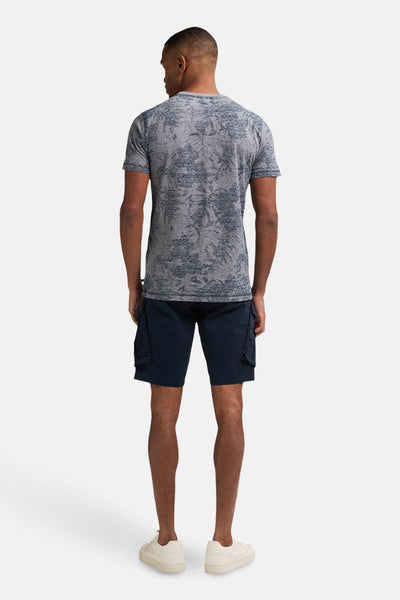 Blauwe korte mouw T-shirt van Petrol Industries, met een gedrukt patroon over de gehele shirt, gedragen met een blauwe marine cargo short.