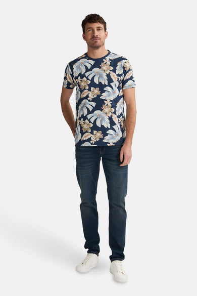 Blauw T-shirt met korte mouwen van Petrol Industries met bloemenprint, gedragen met een blauwe jeans en witte sneakers.