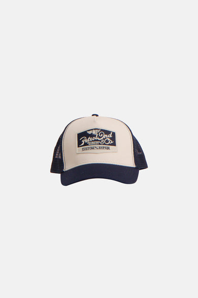 Blauwe pet van Petrol Industries, met beige inzetstuk en logopatch aan de voorkant.