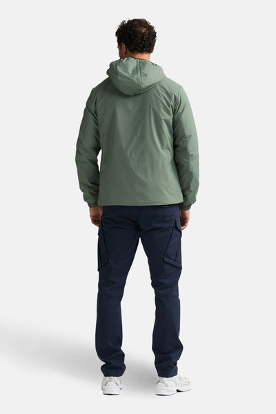 Veste longue kaki de Petrol Industries®, avec capuche et poches cargo, portée avec un pantalon bleu marine et des baskets blanches, vue de dos.
