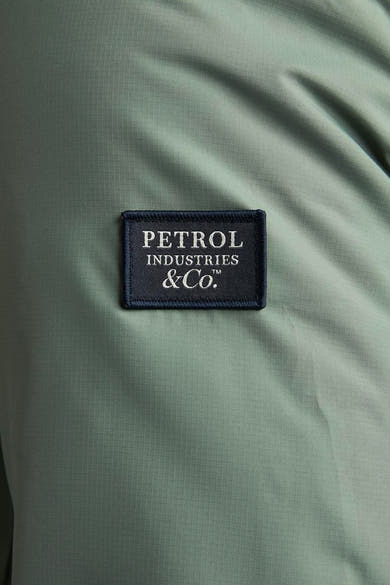 Lange kaki jas van Petrol Industries, met een opgestikt merklogo.