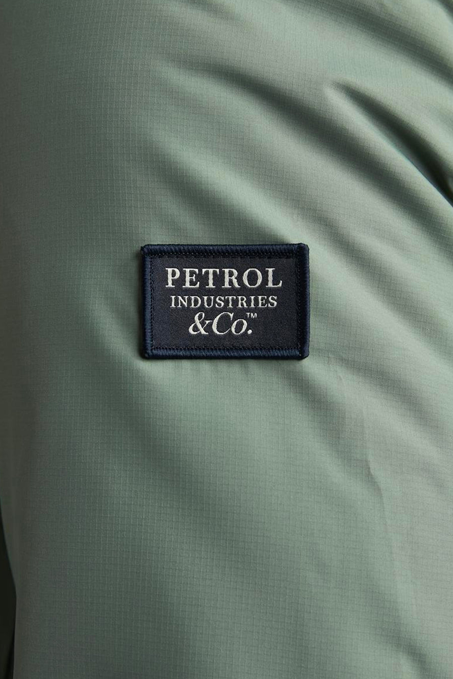 Lange kaki jas van Petrol Industries, met een opgestikt merklogo.