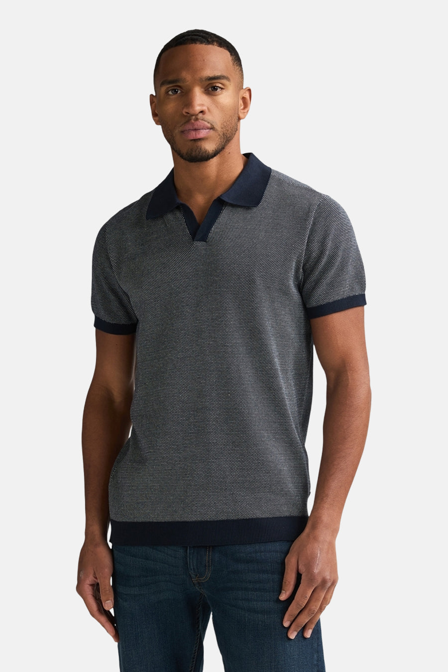 Pull bleu de Petrol Industries®, avec un motif texturé et un col polo bleu marine, porté avec un jean bleu.