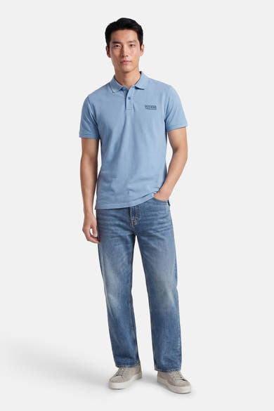Polo bleu à manches courtes de Petrol Industries, porté avec un jean bleu et des chaussures grises.