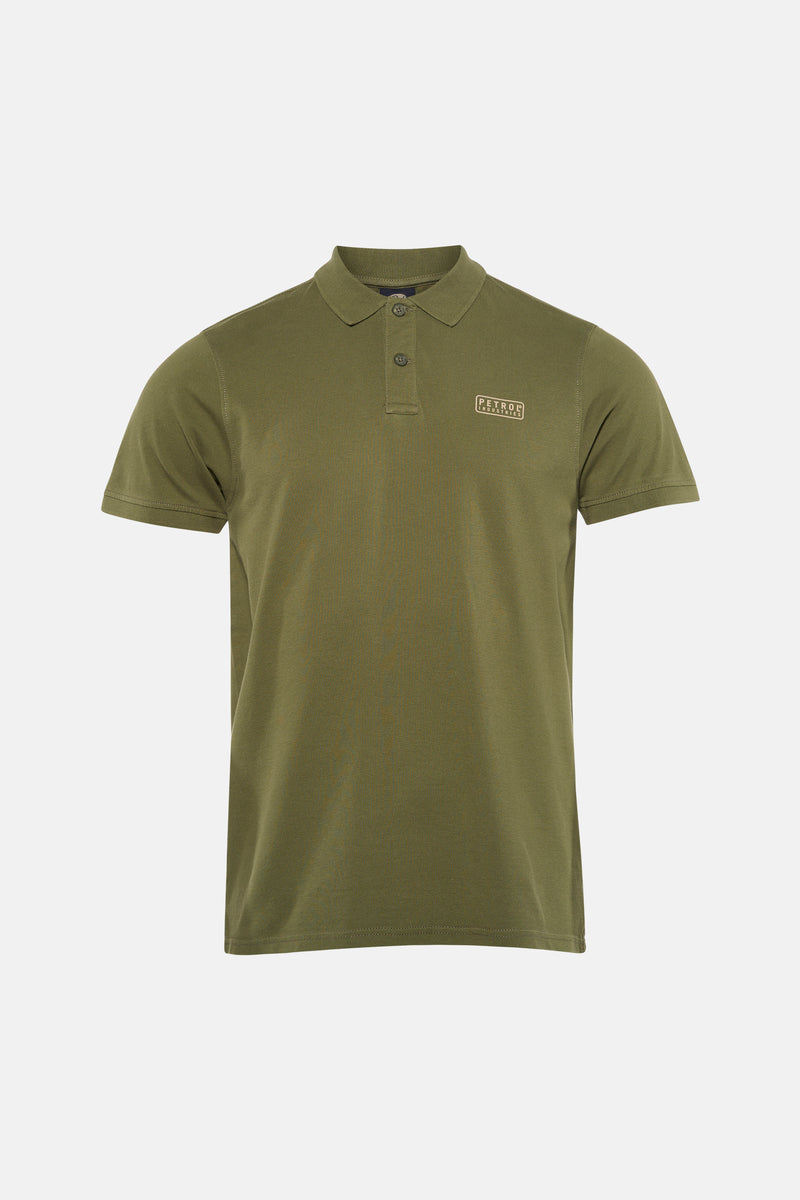 Groen poloshirt met korte mouwen van Petrol Industries®, gedragen met een spijkerbroek en witte sneakers.