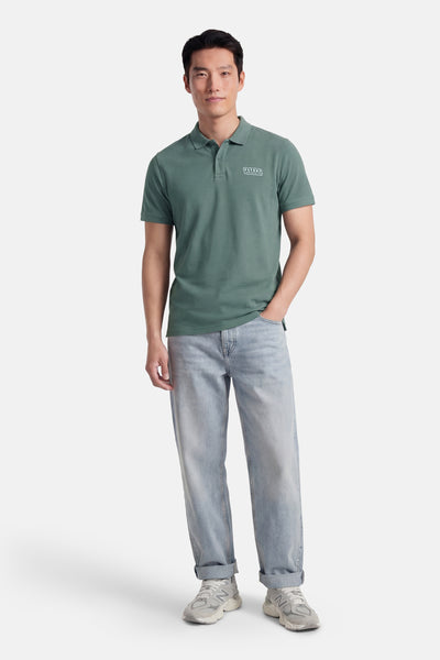 Polo à manches courtes vert de Petrol Industries, porté avec un jean bleu clair et des baskets grises.