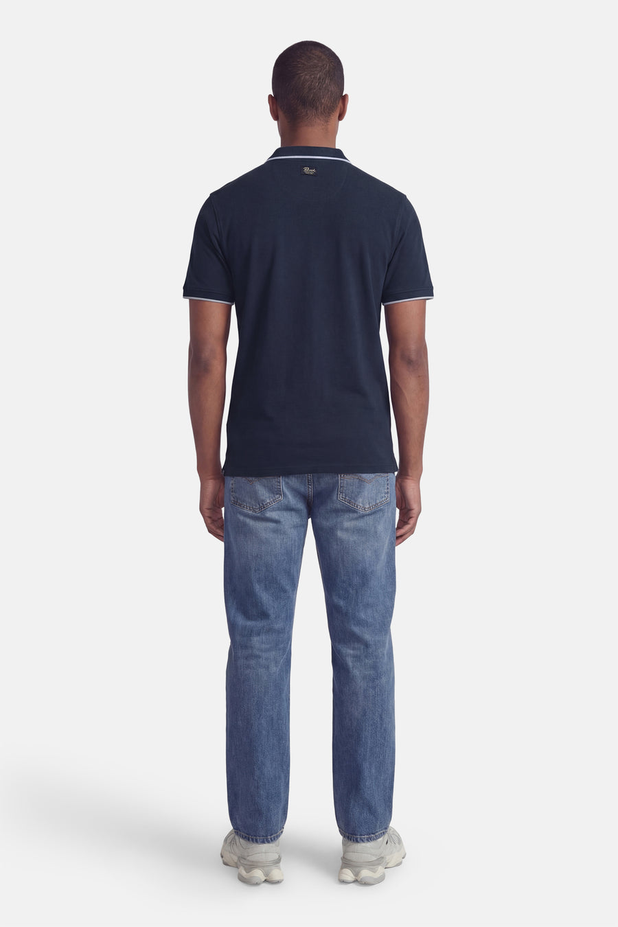 Blauw poloshirt met korte mouwen van Petrol Industries, met kraag en mouwen met witte bies, gedragen met een casual spijkerbroek.