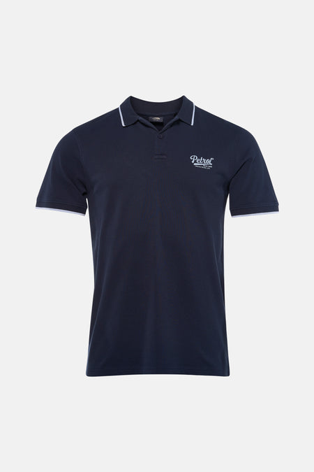 Blauw poloshirt met korte mouwen van Petrol Industries, met witte bies op de kraag en mouwen, gedragen met een spijkerbroek en sneakers.