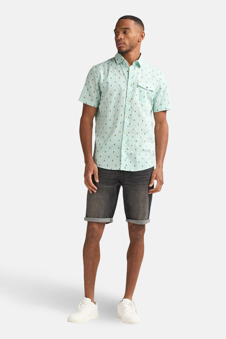 Chemise à manches courtes verte à motif losanges by Petrol Industries®, portée avec un short en jean gris et des baskets blanches.