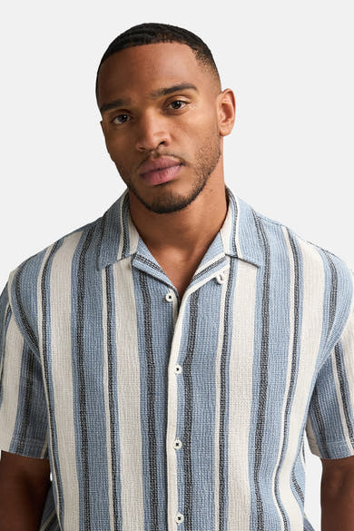 Chemise à manches courtes bleue à rayures verticales par Petrol Industries®, avec une texture gaufrée et un col cubain.