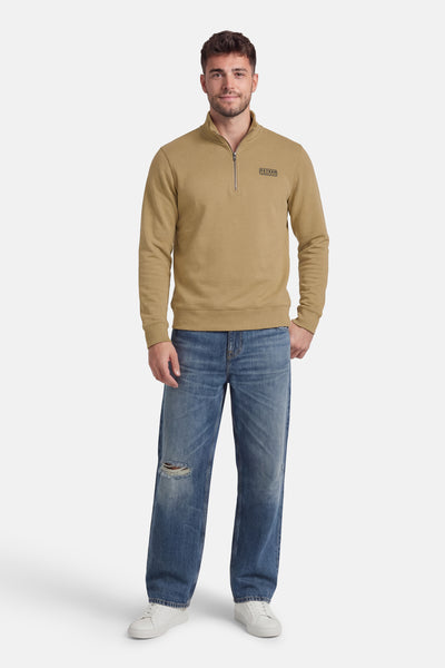 Kaki half-zip sweatshirt van Petrol Industries, gedragen met een wijde blauwe jeans en witte sneakers.