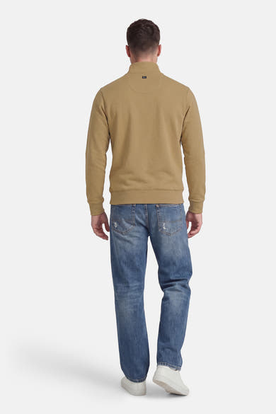 Kaki sweatshirt, van Petrol Industries, met een opstaande kraag en lange mouwen, gedragen met een blauwe jeans en witte sneakers.