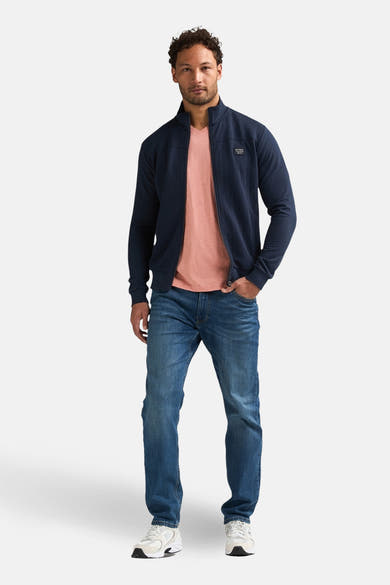 Blauwe sweater met opstaande kraag van Petrol Industries®, gedragen met een roze T-shirt en een spijkerbroek.