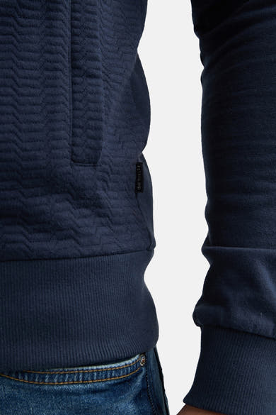 Blauwe sweat-shirt met opstaande kraag van Petrol Industries, met een getextureerd patroon en een geribbelde zoom, gedragen met een blauwe jeans.