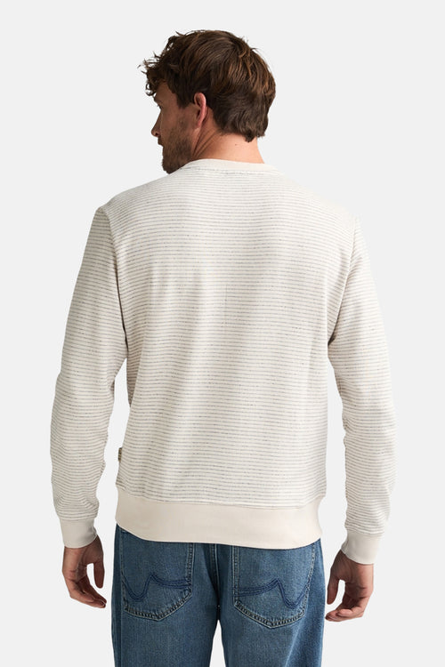 Pull à col rond écru de Petrol Industries®, avec motif rayé horizontal et manches longues, porté avec un jean bleu.