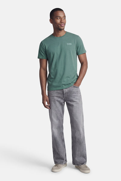 T-shirt à manches courtes vert de Petrol Industries®, porté avec un jean gris délavé et des baskets beiges.