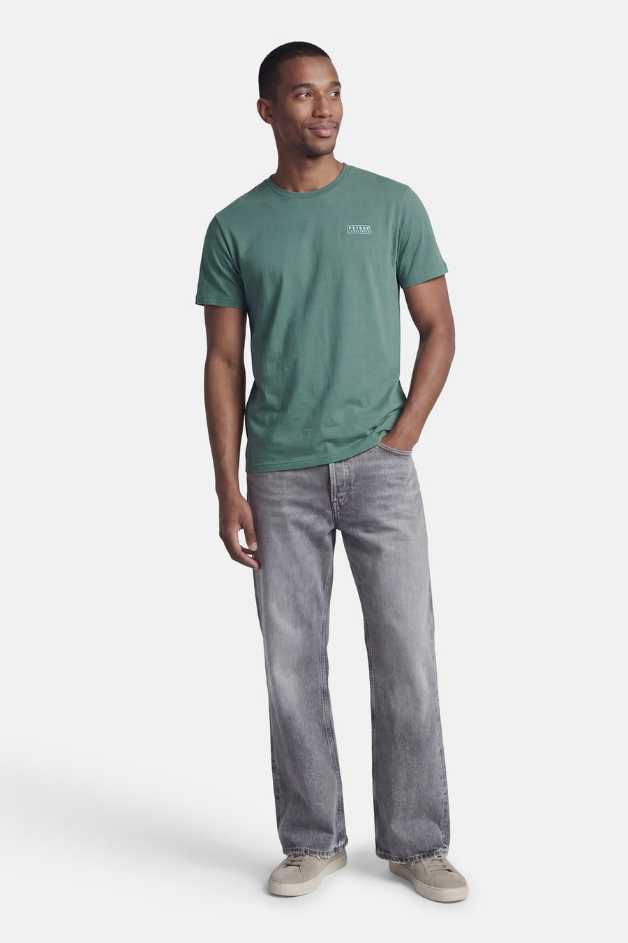 T-shirt à manches courtes vert de Petrol Industries®, porté avec un jean gris délavé et des baskets beiges.