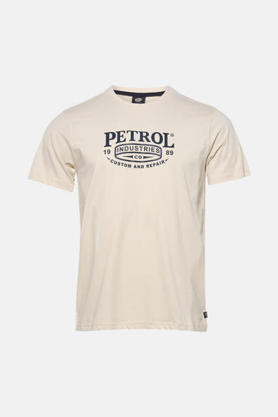 Ecru T-shirt met korte mouwen van Petrol Industries, met een grafische print op de voorkant, gedragen met een grijze jeans en sneakers.