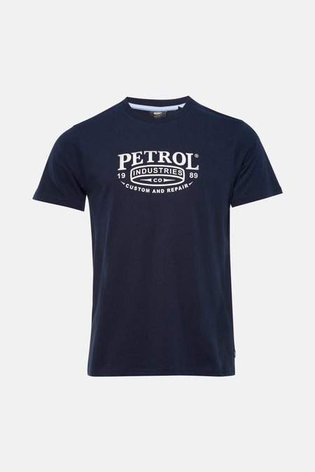 Blauw T-shirt met korte mouwen van Petrol Industries, gedragen met een wijde, verbleekte spijkerbroek en grijze sneakers.