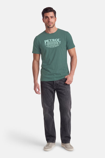 T-shirt à manches courtes vert de Petrol Industries®, porté avec un jean gris foncé et des baskets basses beiges.
