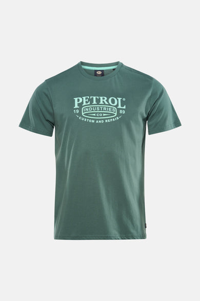 Groen T-shirt met korte mouwen van Petrol Industries®, gedragen met een donkergrijze jeans en beige lage sneakers.